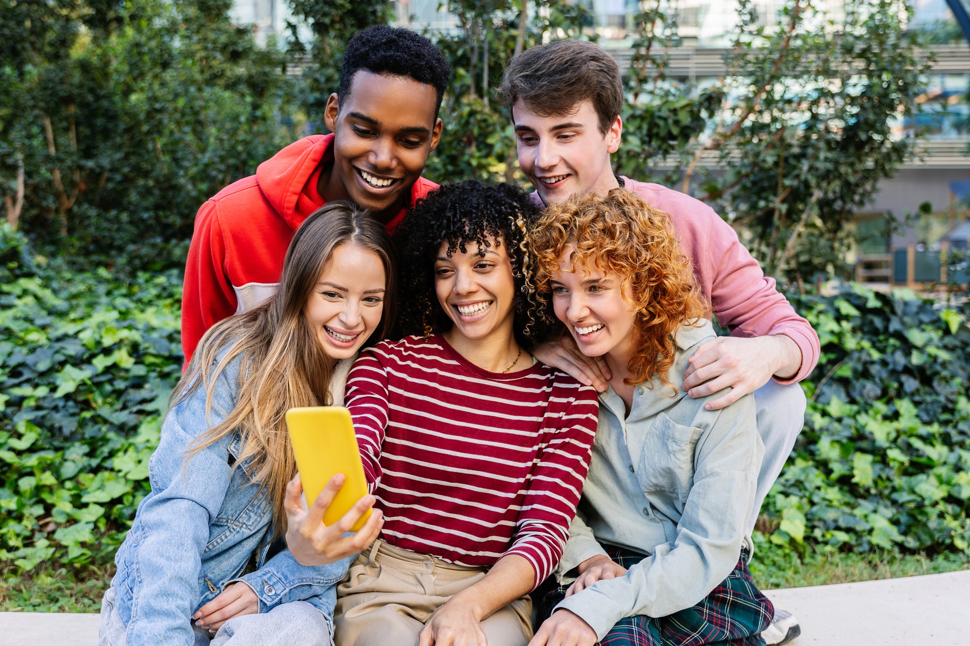Young group of teenage friends watching social media content on smart phone app