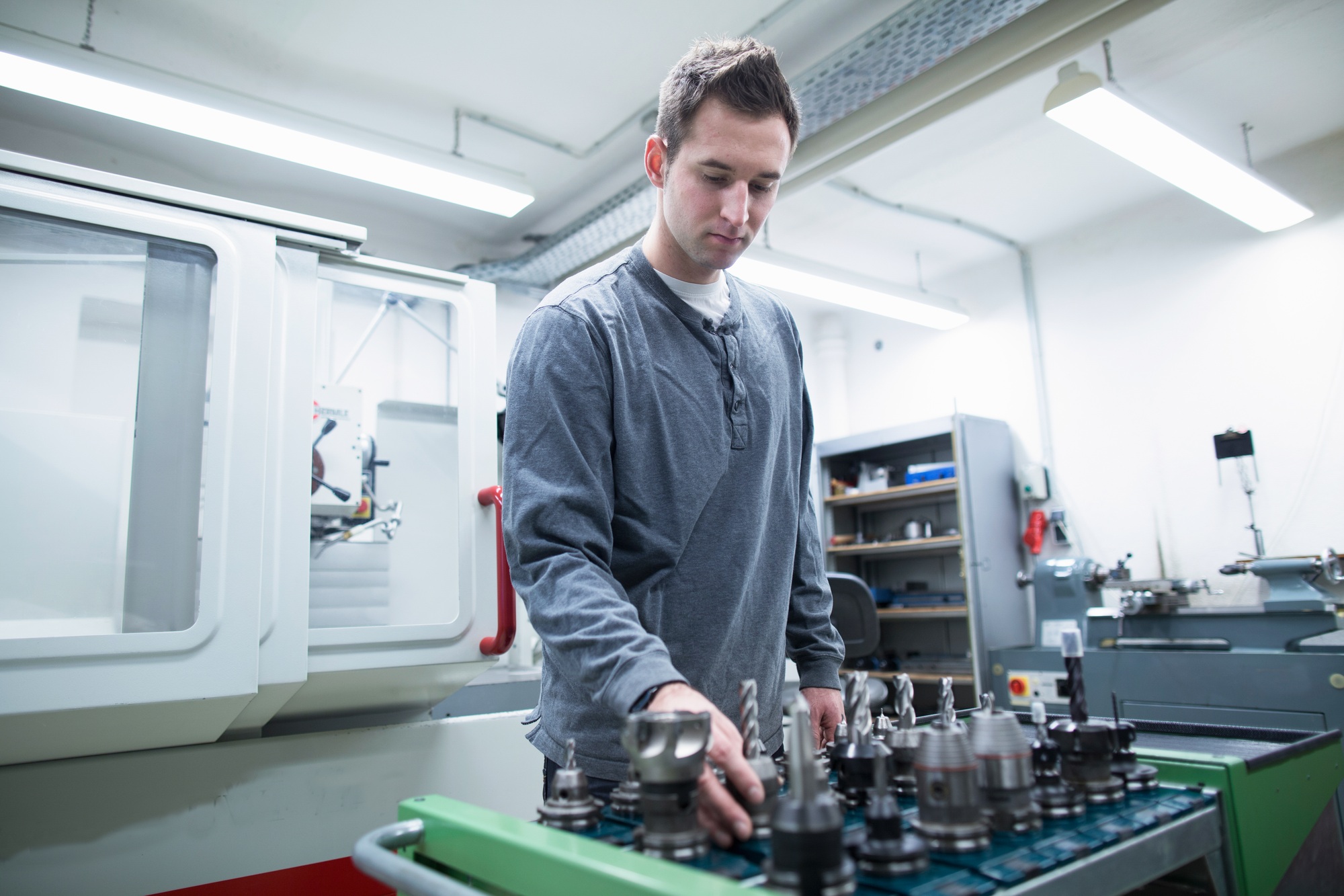 Young male technician choosing drill bit in workshop