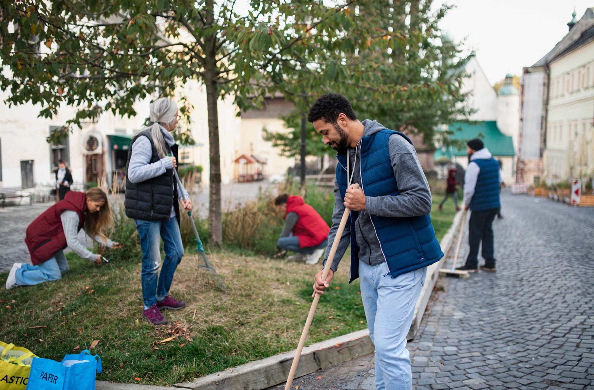 Young man volunteer with team cleaning up street, community service concept