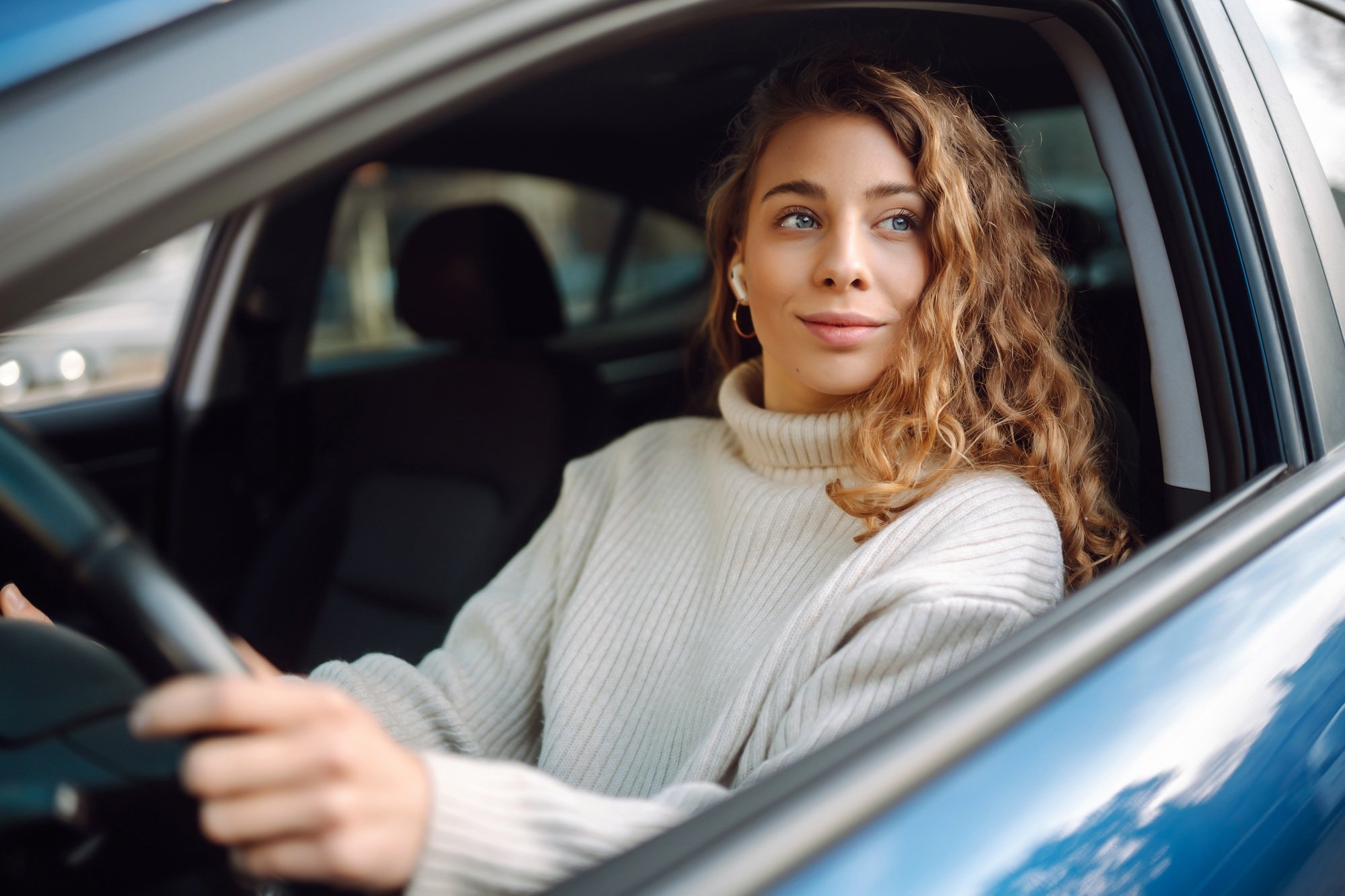 Young woman driving a car in the city. Car sharing, rental service or taxi app.