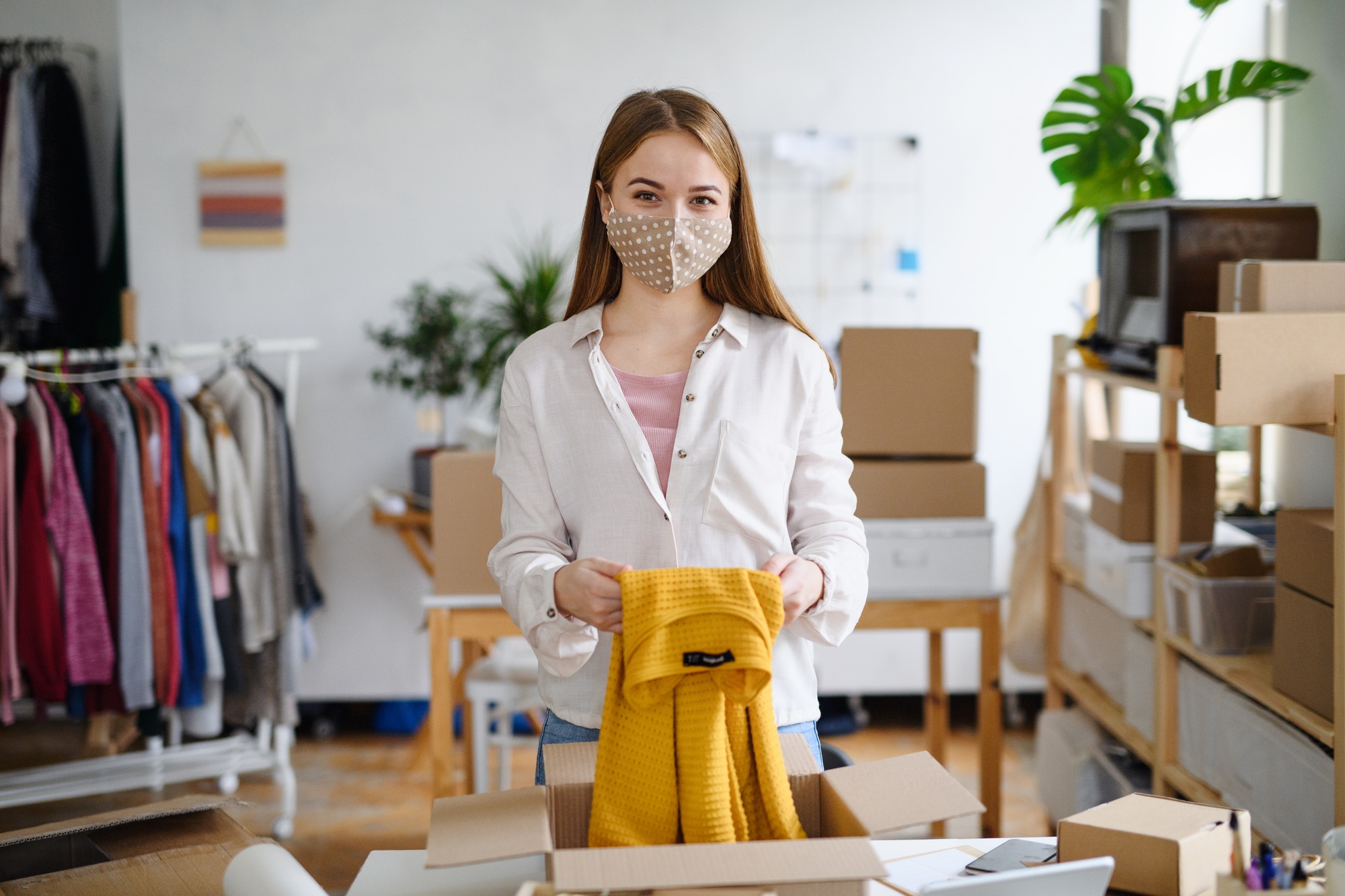 Young woman dropshipper working at home, processing orders. Coronavirus concept.