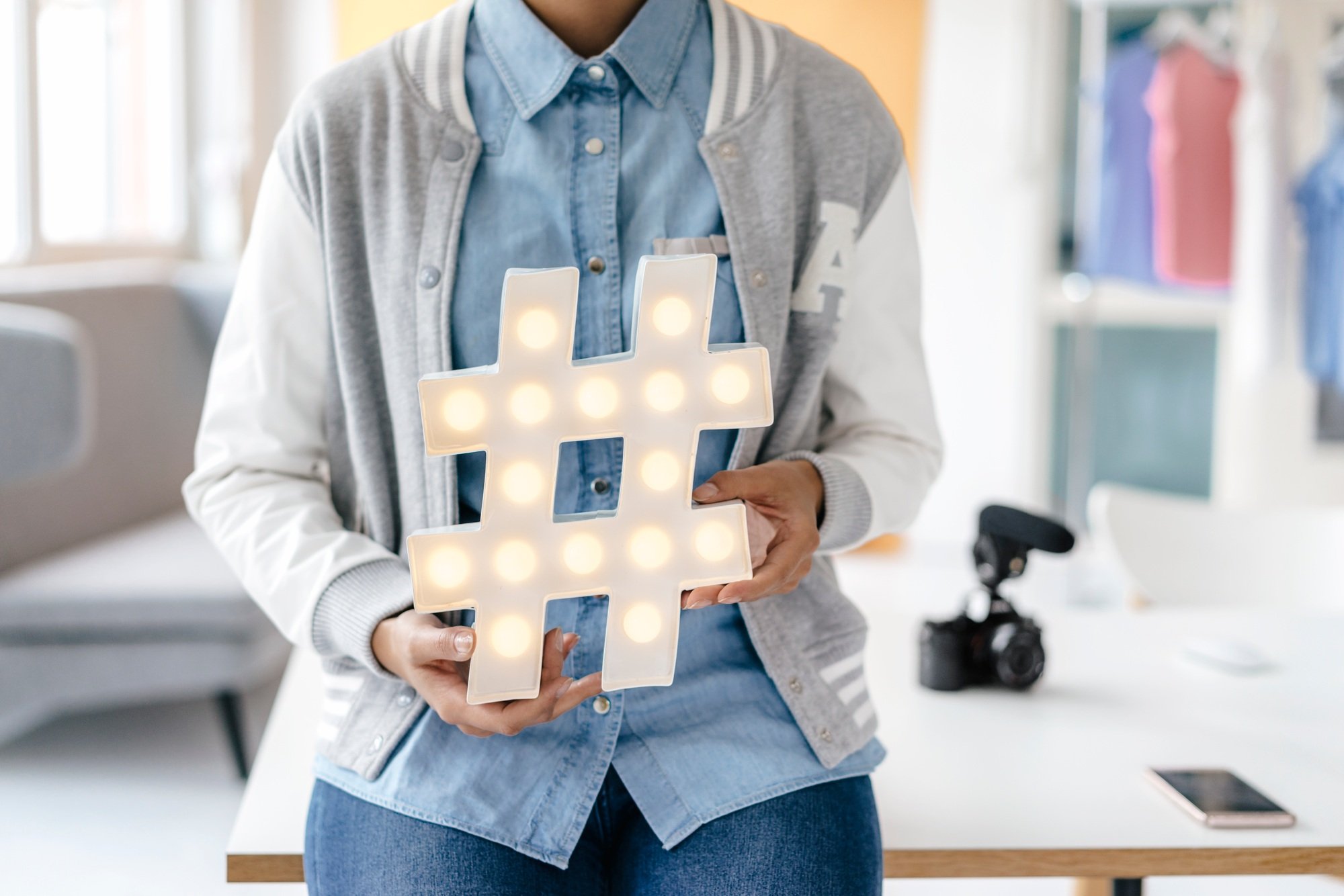 Young woman holding hashtag sign in studio