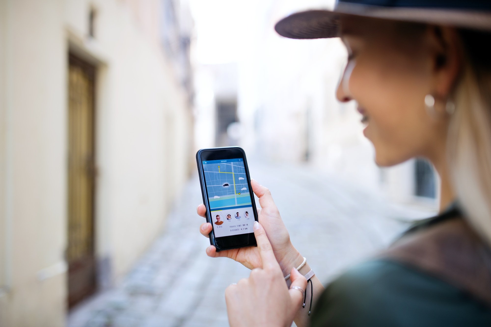 Young woman traveler with smartphone in city on holiday, car sharing concept